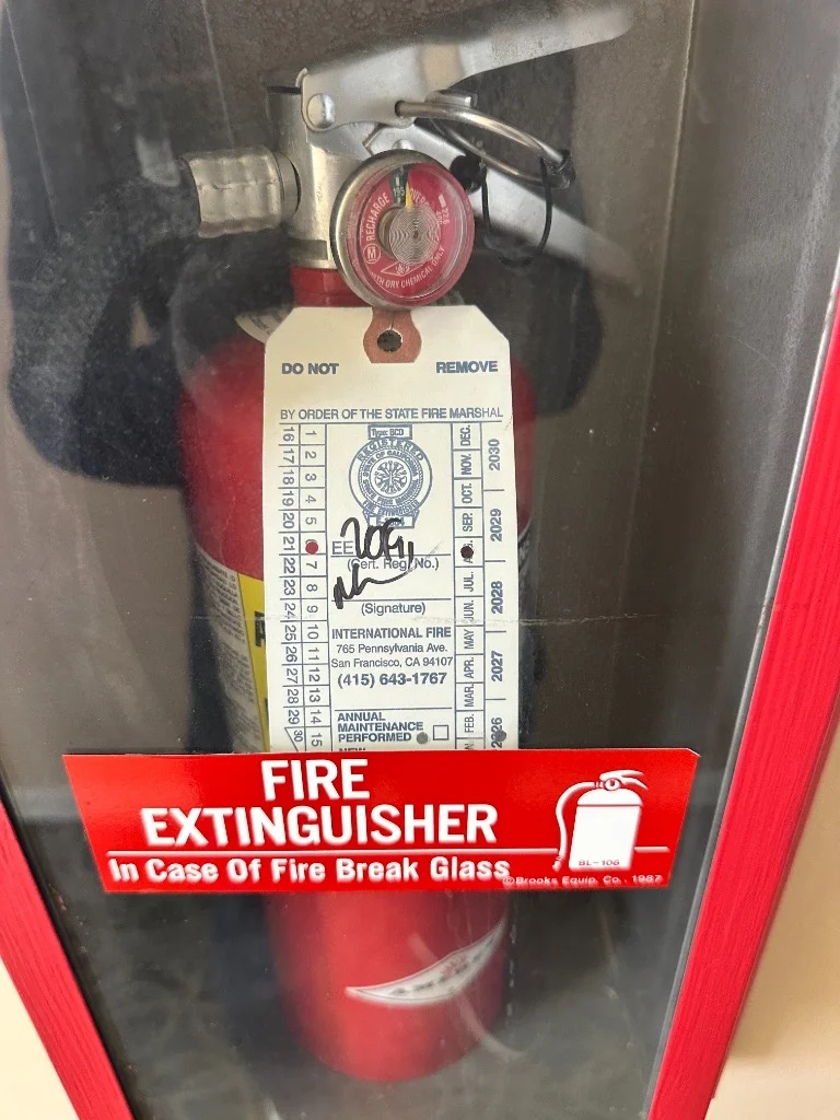 Wall-mounted glass front fire extinguisher cabinet at commercial facility restaurant in Richmond District, San Francisco.