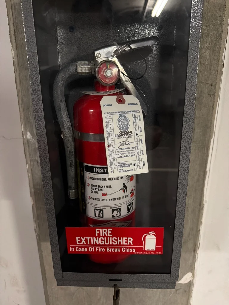 Amerex fire extinguisher inside a cabinet with a new inspection tag at a residential building in Mission Dolores