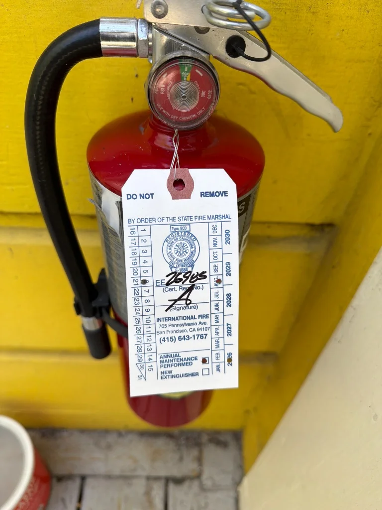 Wall-mounted portable fire extinguisher next to exterior entry door at Mission District, San Francisco, CA multi-unit building in Mission District, San Francisco.